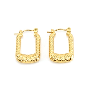 Macro view of gold rectangular earrings featuring detailed textured relief pattern