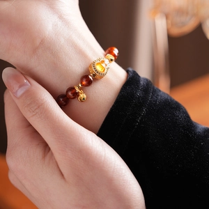 Detail of red garnet bracelet with a golden heart pendant featuring yellow center stone