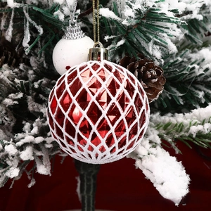 Close-up of red diamond textured and white speckled Christmas balls on snowy pine branches