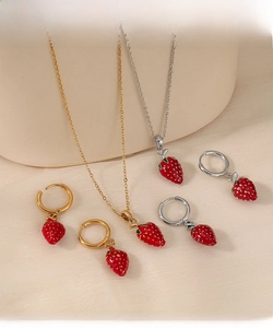 Close-up of strawberry pendant necklaces and hoop earrings in gold and silver finishes