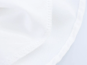 Close-up of white textile fabric texture showing detailed edge stitching and woven mesh