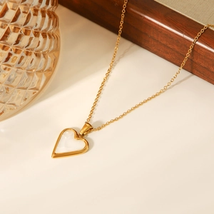 Macro detail of golden heart pendant necklace with white shell inlay and sleek metal chain