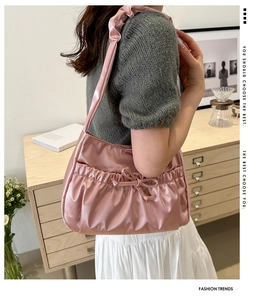 Gros plan du sac en satin rose avec cordon, nœud décoratif et bandoulière froissée