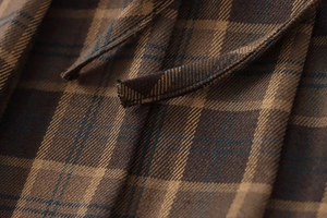 Close-up of the brown plaid woven fabric and fabric tie on this mini skirt detail