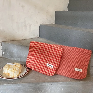 Detalle de neceseres de jacquard a cuadros rojos con etiqueta Sozakka en cemento