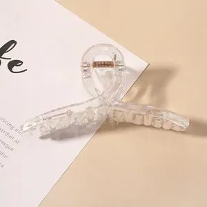 Close-up of a transparent iridescent hair claw clip with golden metal spring detail