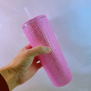 Detail shot of a large pink rhinestone studded tumbler cup with a clear reusable straw