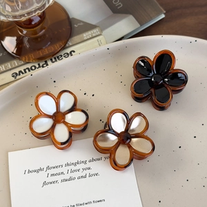 Three vintage amber flower hair claws in black white and gold on a decorative plate