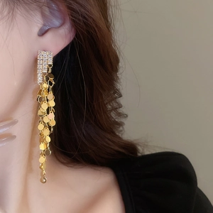 Detail of long gold tassel earrings with zircon studs on model for a trendy elegant look