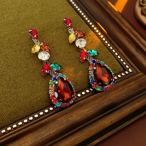 Detail of vintage teardrop earrings with red main stone and colorful rhinestones on velvet