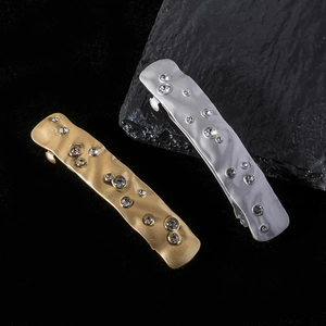 Detail showing irregular textured gold and silver hair clips with sparkling rhinestones