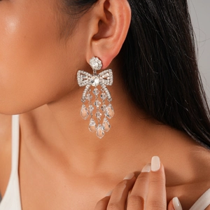 Detail of silver bow earrings featuring crystal tassels and teardrop pendants