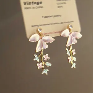 Detailed view of pearlescent floral tassel earrings with zircon studs on a display card