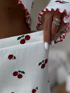 Detail of ribbed knit fabric with cherry print and red lettuce edge on women's pajamas