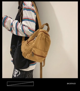Seitenansicht des senfgelben Mini-Rucksacks aus Leinwand mit Reißverschlusstaschen und Gurten