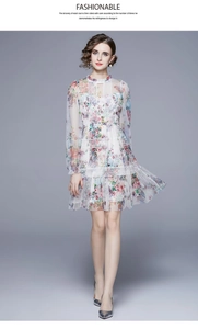 Detail der zarten Spitzenborte an einem weißen floralen Kleid mit Netzärmeln