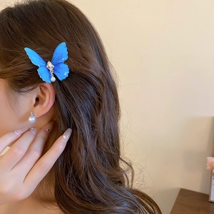 Vue détaillée d'une pince à cheveux papillon bleue avec perles et ailes dégradées sur modèle