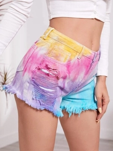 Detail shot of colorful tie-dye high-waist denim shorts with ripped holes and frayed edges