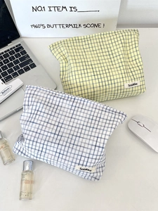 Checkered fabric cosmetic bag set in pale yellow and off-white on a desk