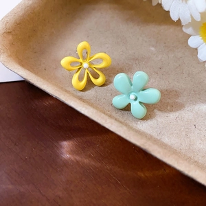 Gros plan de boucles d'oreilles fleurs asymétriques jaune et vert menthe mat