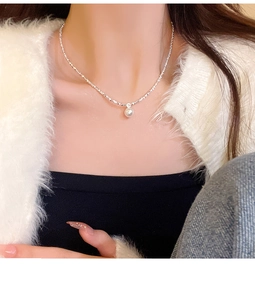 Close-up of minimalist silver chain necklace with a round white pearl pendant on a model