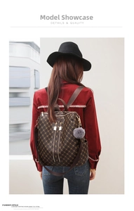 Detail of dark brown monogram backpack with gold zippers and grey pompom keychain accessory