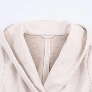 Detailed close-up of stitching and premium wool texture on a beige hooded coat