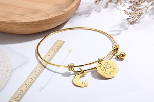 Detail of adjustable star and moon gold stainless steel bangle with a round charm pendant