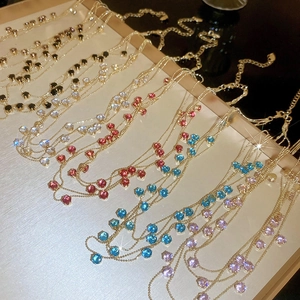 Detail view of multi-layered gold necklaces with colorful round zircon gemstone accents
