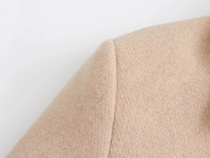 Detailed view of shoulder stitching on a camel wool blend jacket with metal button