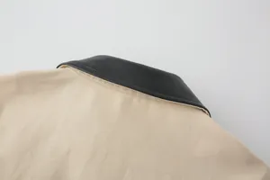 Close-up of beige twill jacket collar with black faux leather contrast and neat stitching
