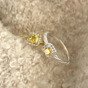 Detail of 925 silver twist rings with square yellow gemstone and pavé halo setting
