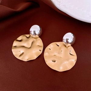 Detail of vintage bicolor metal earrings with golden hammered disc and silver sphere