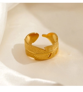 Macro shot of gold feather ring with detailed textures on white silk background