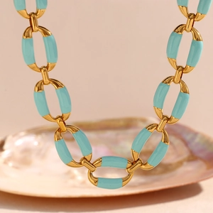 Close-up of 18K gold-plated chain necklace with turquoise enamel links on a seashell