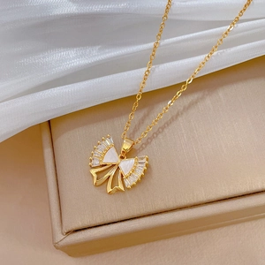 Detail of gold bow necklace with mother-of-pearl and zircons on a luxury jewelry box