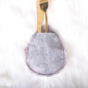 Christmas faceless gnome cutlery bag with gold fork and knife on white plush background