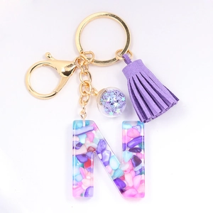 Detailed view of resin letter N keychain with purple tassel and shell flake inlay