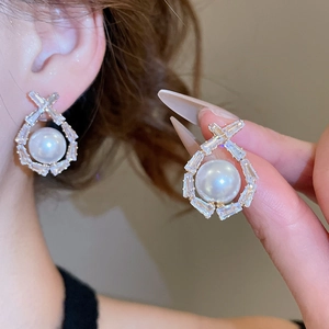 Detailed close-up of pearl and cubic zirconia drop earrings worn on ear showing elegant texture