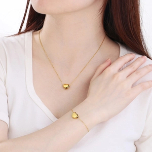Parure collier et bracelet cœur en acier inoxydable plaqué or 18 carats sur mannequin