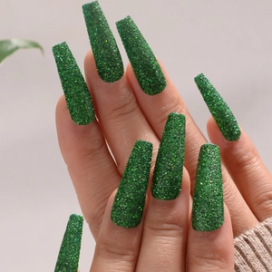 Macro shot of long coffin fake nails in dark green with sparkly glitter finish