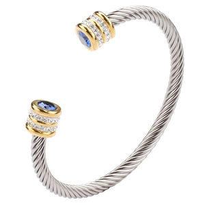 Macro detail of silver twisted cable bracelet with gold accents and blue gemstones