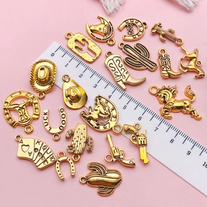 Pendentifs dorés style western avec cactus et chapeau à côté d'une règle graduée