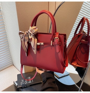 Detailed view of burgundy handbag with silk scarf handle and elegant metal buckle