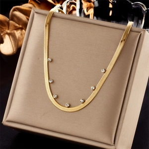 Close-up of golden flat snake chain necklace with sparkling zircon stones in a jewelry box