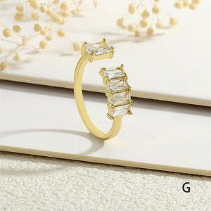 Detail of gold open ring with rectangular zircon stones on white paper background