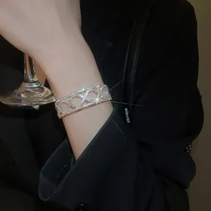 Close-up of elegant silver crisscross bracelet with pavé diamonds worn by a model