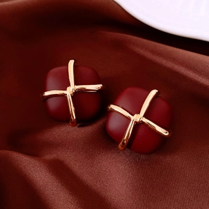 Detail of burgundy gift box earrings with golden cross lines on silk fabric
