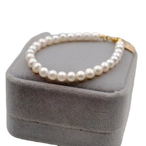 Elegant freshwater pearl bracelet with gold clasp on a velvet jewelry display tray