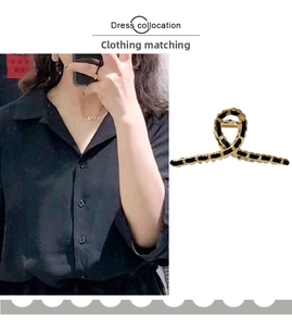 Detail of elegant black ribbon wrapped gold shark hair clip in cross hollow design